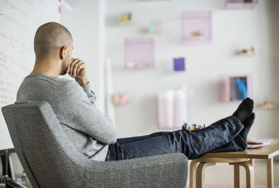 Side view of young man sitting on chair