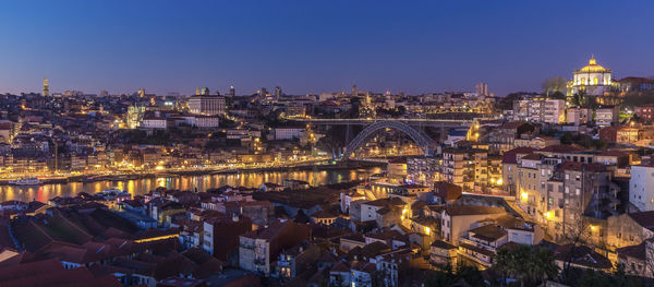 High angle view of illuminated buildings by river against sky