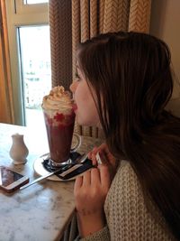 Midsection of woman holding ice cream on table