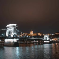 Illuminated bridge over river at night