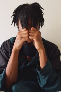 Man with dreadlocks sitting against wall