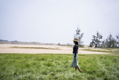 Rear view of man standing on field against clear sky