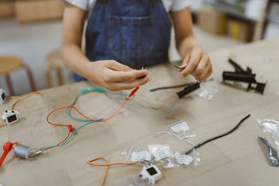 Midsection of student connecting electrical wires on table at school workshop