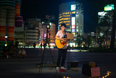 Woman standing at illuminated city during night