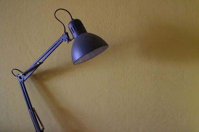 Close-up of electric lamp on table against wall