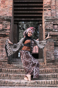 Portrait of young woman wearing traditional clothing dancing on steps