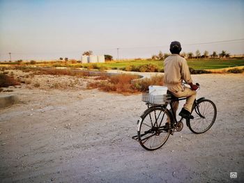 Rear view of man with bicycle on road