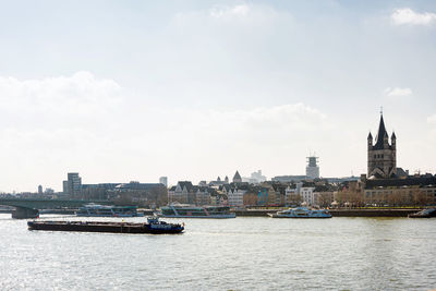 View of buildings by river against sky in city