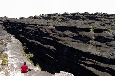 Rear view of people on rock formations against clear sky