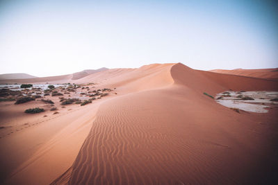 Sand dunes in desert against clear sky