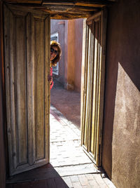 Woman wearing sunglasses standing behind door