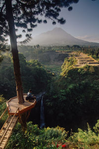 Man sitting on mountain against sky