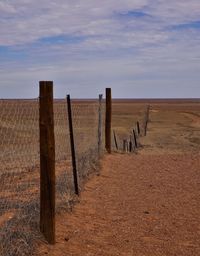 Wooden fence on field against sky