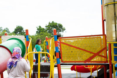 Asian toddler playing at the colourful playground in the morning.