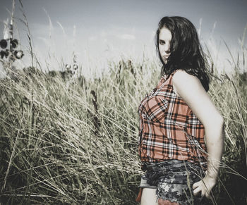 Young woman looking at camera on field against sky