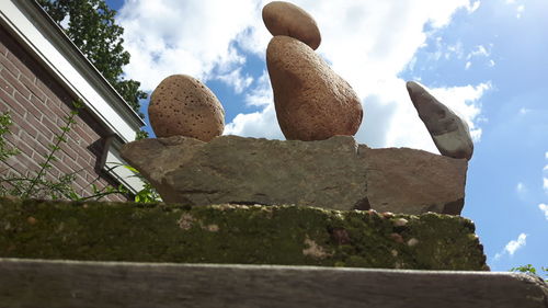 Low angle view of stone wall against cloudy sky