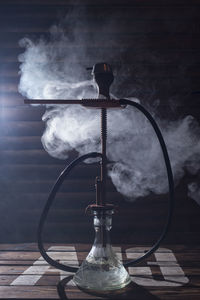 Close-up of smoke emitting from hookah on table