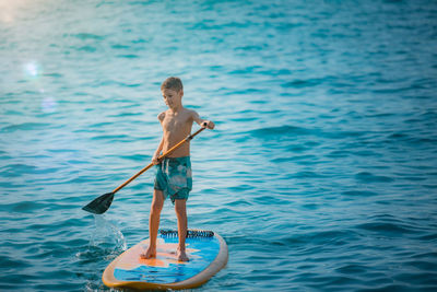 Full length of shirtless boy standing in sea