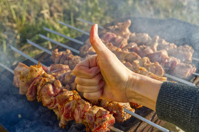 Midsection of person preparing food on barbecue grill