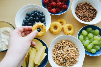 Cropped image of hand holding dessert over table at home