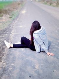 Rear view of woman sitting on street