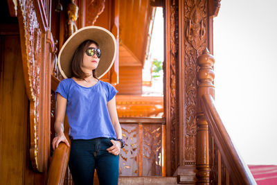 Portrait of young woman standing against building
