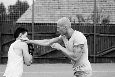 Side view of young male trainer teaching boxing to boy