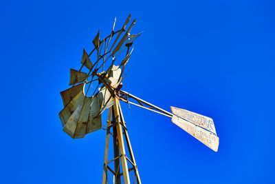 Low angle view of electricity pylon against clear blue sky