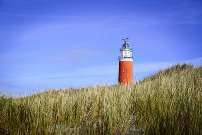 Lighthouse on field against sky