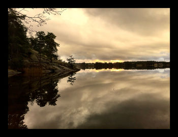 Scenic view of calm lake against cloudy sky