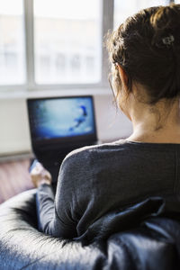 Rear view of mature businesswoman using laptop while sitting on bean bag in office