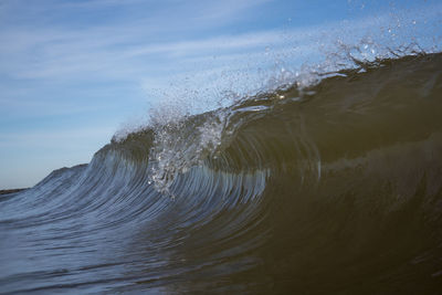 Close-up of sea waves splashing on shore against sky