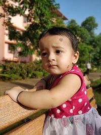 Close-up of cute baby girl looking away on bench in park