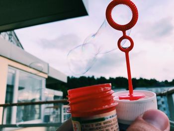 Close-up of hand holding drink against sky