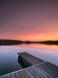 Pier over lake against sky during sunset