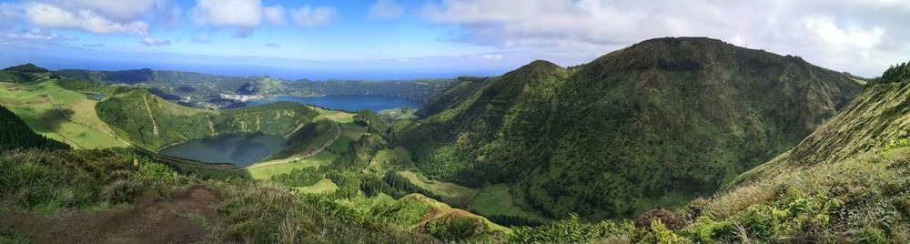 Panoramic view of green landscape and mountains against sky