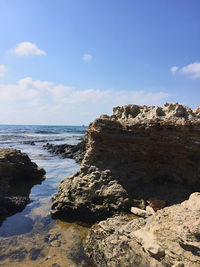 Rock formation on beach against sky