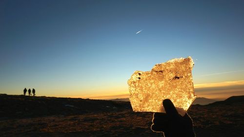 Silhouette man standing on rock against sky during sunset