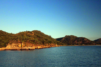 Scenic view of sea and mountains against clear blue sky