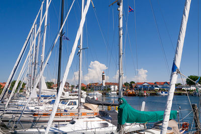 Sailboats moored at harbor against blue sky