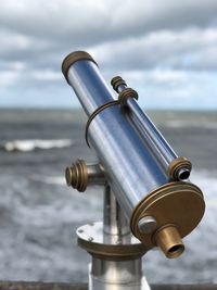 Close-up of hand-held telescope against sky