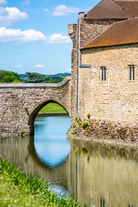 Arch bridge over river by building against sky