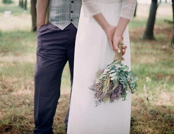 Midsection of couple standing on grassy field