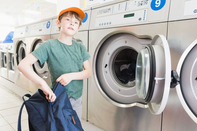 Boy using washing machine in room