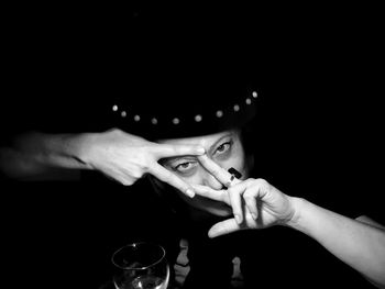 Portrait of woman gesturing against black background