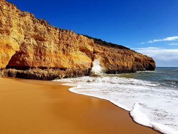 Rock formations on beach against sky