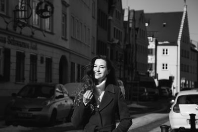 Portrait of young woman standing on street in city