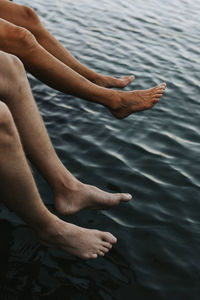 Low section of people sitting at sea barefoot