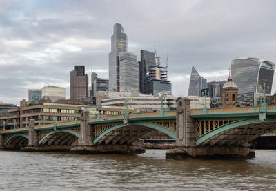 Bridge over river in city against sky