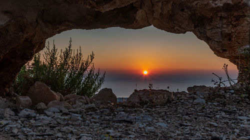 Rock formation on beach against sky during sunset